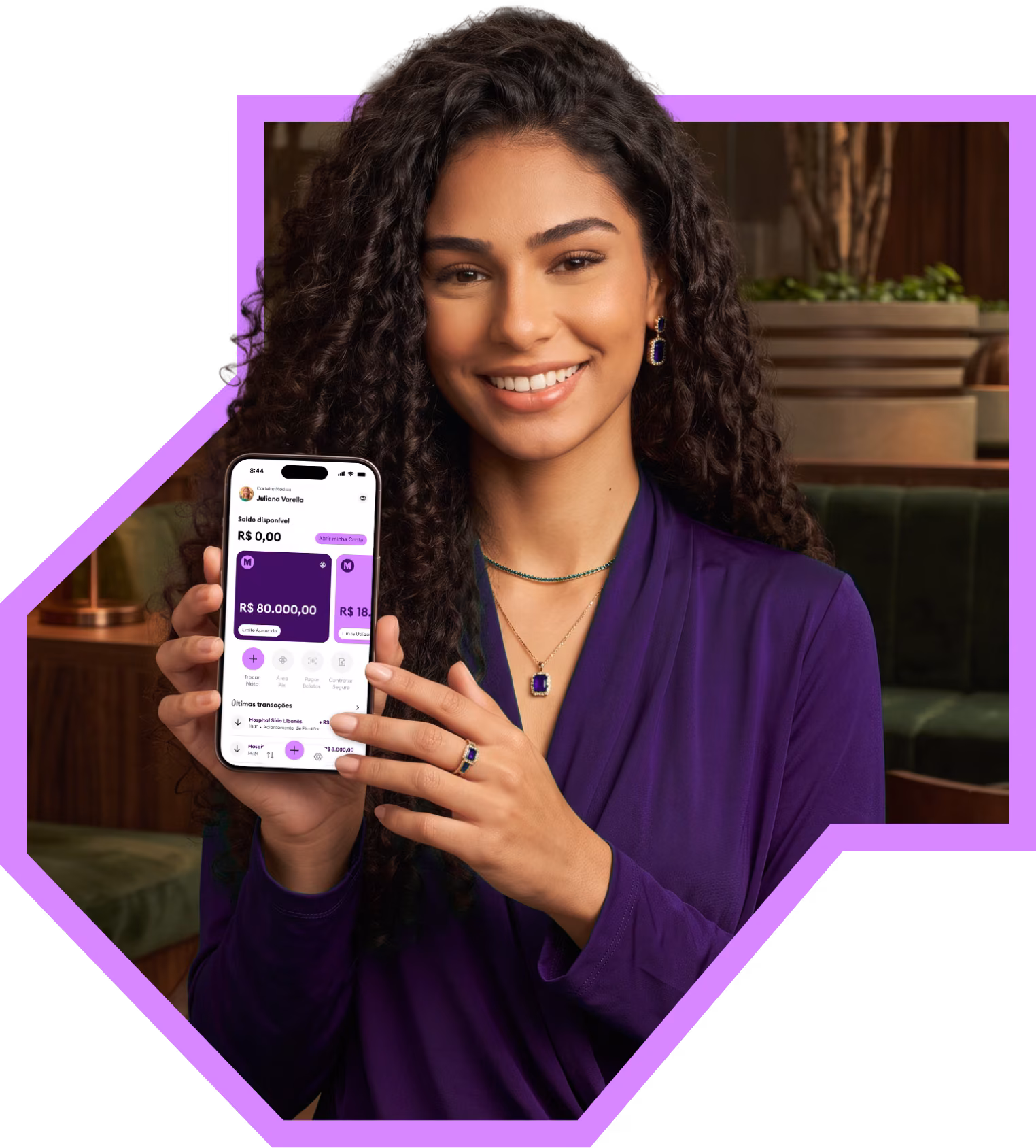 Médica sorrindo segurando o celular com o app da Medcred aberto